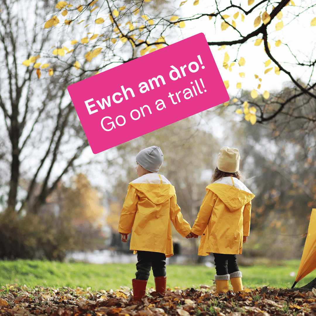 Two children in raincoats waiting to go on a trail. Dau o blant yn eu cotiau glaw yn aros i fynd am dro.